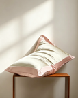 Pink and white pillow on a wooden stool against a beige wall with soft shadows. 100% 6A Grade Mulberry silk, 40 momme