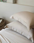 Neatly made bed with white bedding and pillows, featuring Tencel logo - TENCEL™ Lyocell