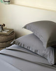 Gray bedding set with pillows on a bed in a bedroom setting, featuring Tencel branding - TENCEL™ Lyocell