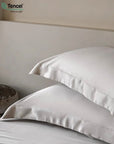 White satin pillows on a bed with Tencel logo in the corner - TENCEL™ Lyocell