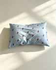Light blue silk pillowcase with red cherry pattern on a white surface