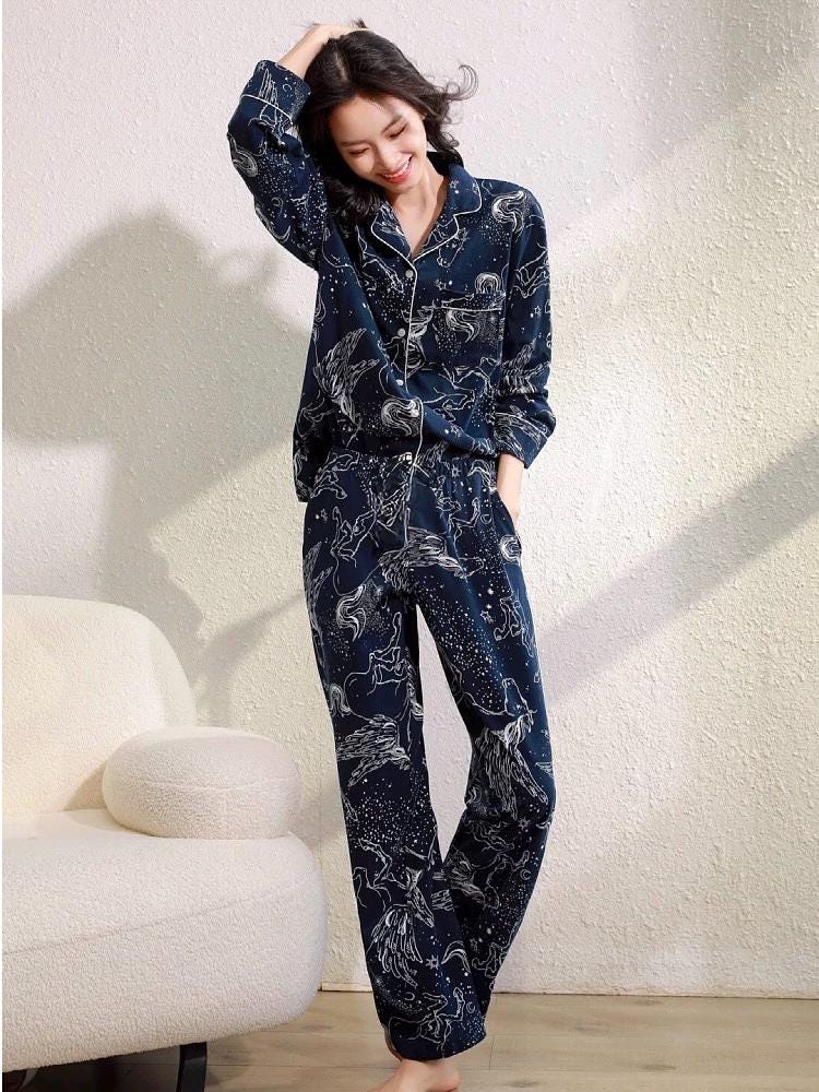 A blue pajama set with a white print of stars and horses. The pajamas have a long-sleeved shirt with a collar and button closure and long pants with a straight leg.